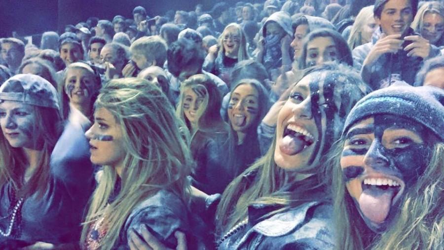 Lauren Miller and Nina Peot, seniors, take a selfie during the football game against Whitefish Bay, capturing the powder the student section tossed in the air during half-time. 