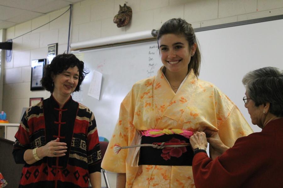 Maggie Hadcock, senior, smiles as Mrs. Grimm dresses her in a kimono. 