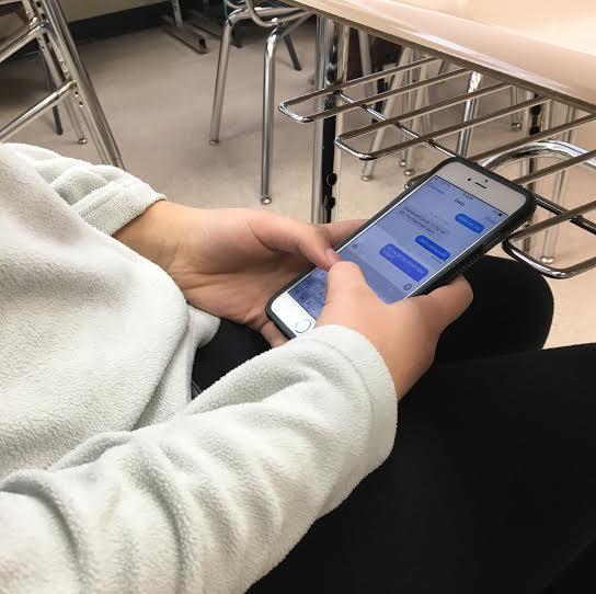 A student texts her father underneath her desk in hopes of avoiding a detention.