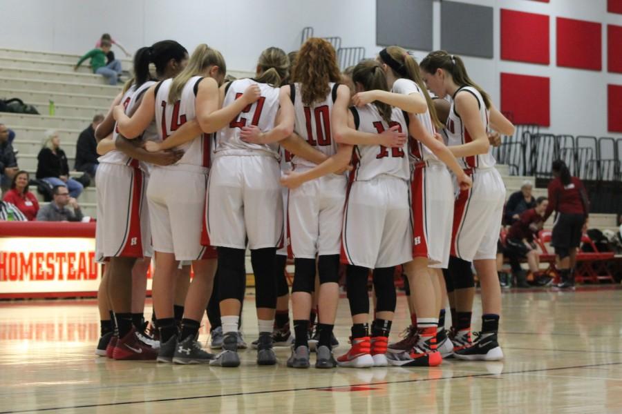 The girls basketball team huddles in pre-game and prepares for the game.