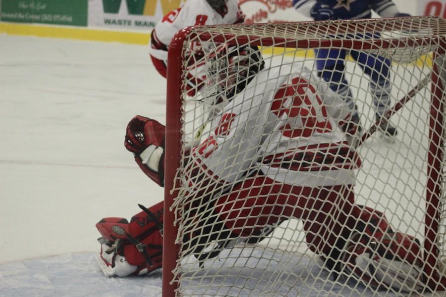 Connor McPike, senior goalie, reaches out to grab the puck before it goes into the net, saving a goal from being scored.