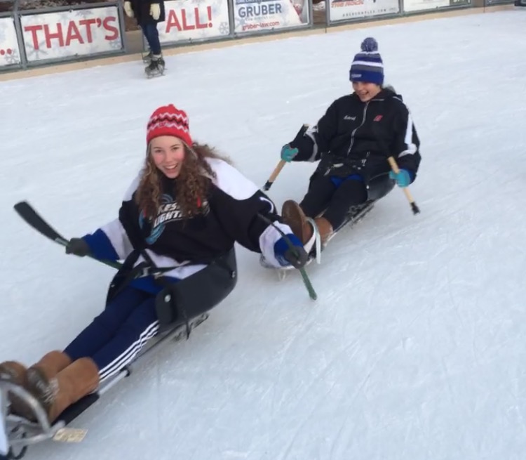 Paige Weir and Lindsey Schimpf, freshmen, glide around the rink on their sleds. 