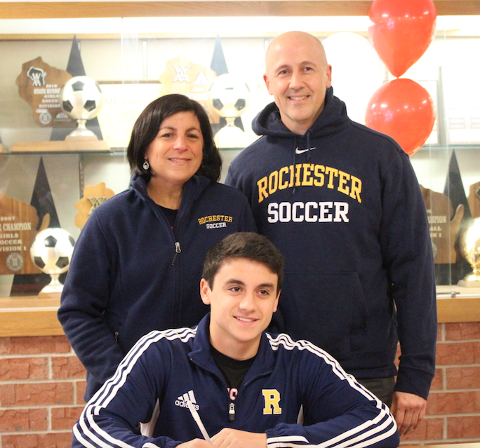 Supporting both of their athletes, Julie and Ryan Cooley stand alongside Josh Cooley, senior, who is committed to play Division III soccer at the University of Rochester. 
