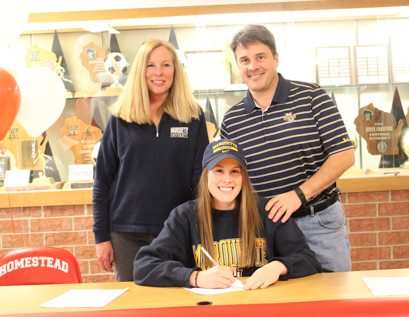 Mary Kate Simon, senior, smiles with proud parents, Susie Simon and Chris Simon as she officially commits to play Division I soccer at Marquette University. 