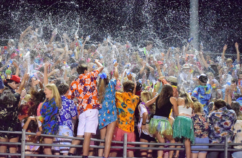 The Homestead student section throws water at half time. The students came dressed in Hawaiian clothes for the luau themed game. “I wouldn’t want to belong to any other student section,” Skylar Pak, senior, said.