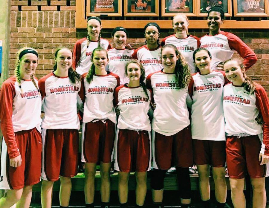 The girls varsity basketball team smiles for a photo. 