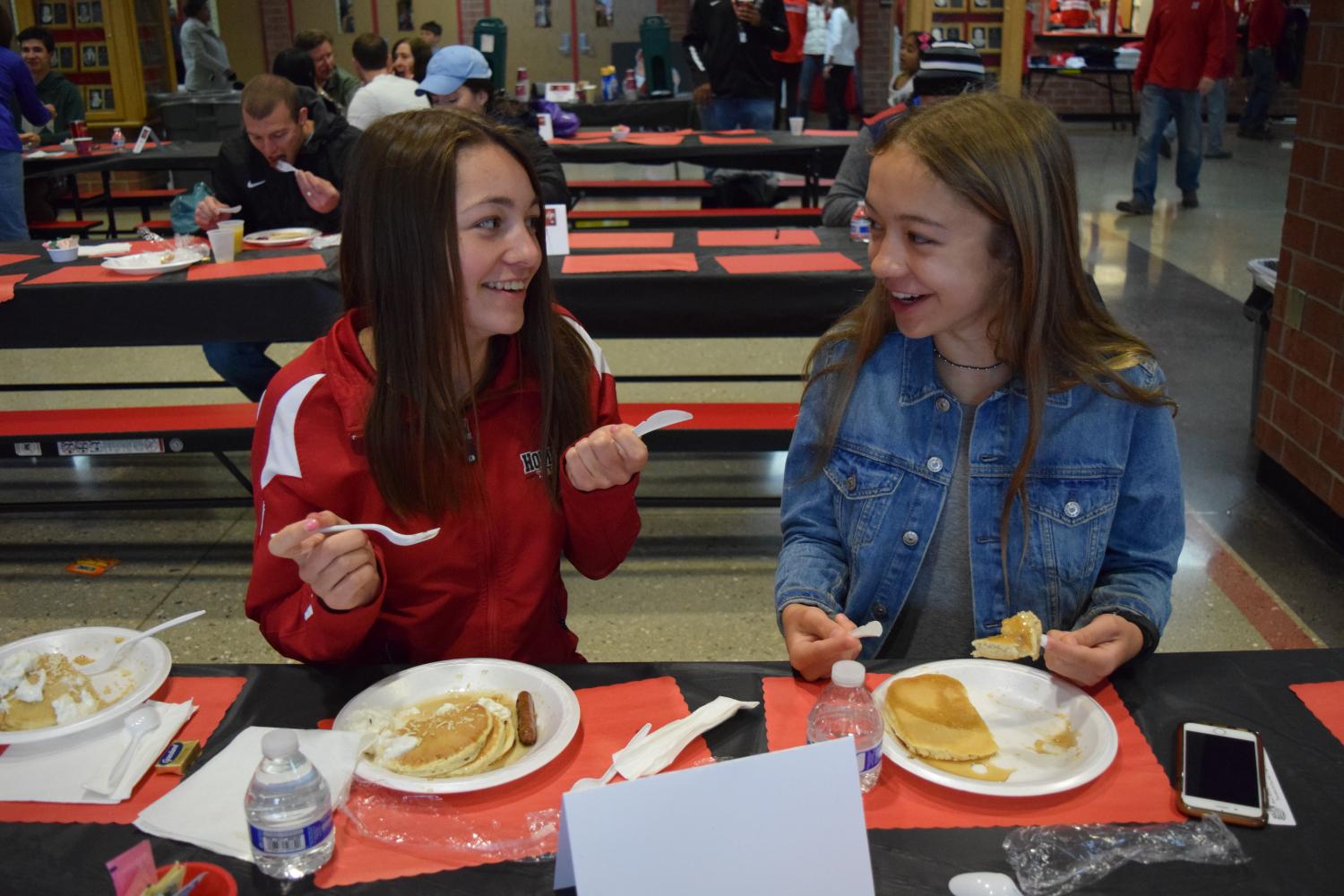 Addie Damron, junior, and Ava Wojnowski, freshman, have a laugh over pancakes.