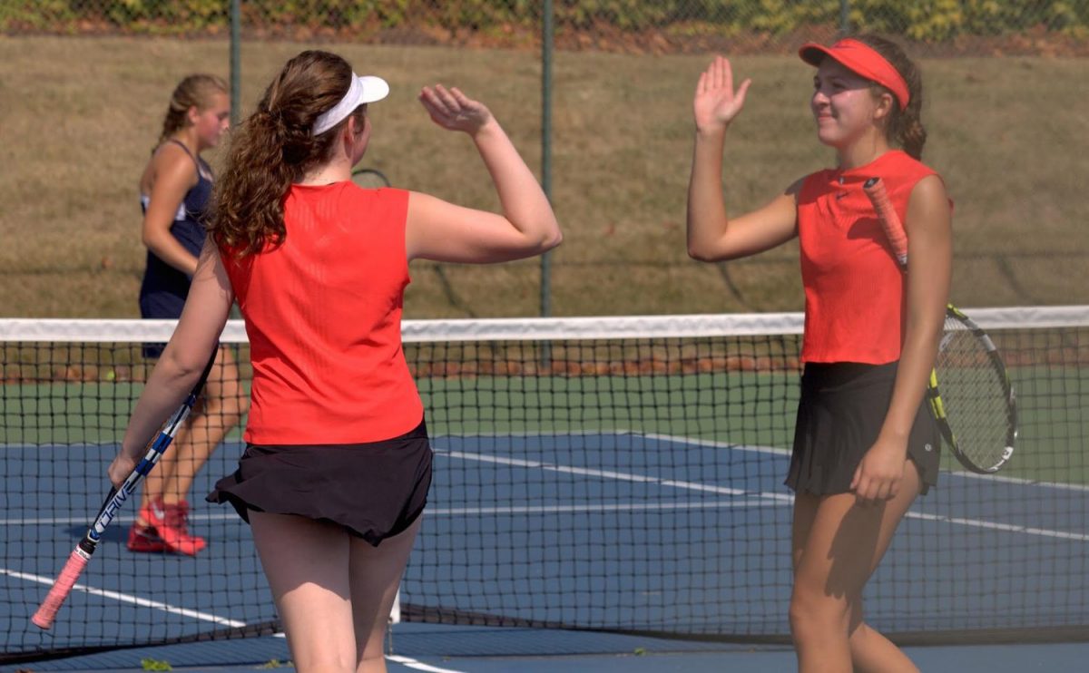 Doubles partners Sasha Milbeck, senior and Ashley Chavin, sophomore, high five during a point. 