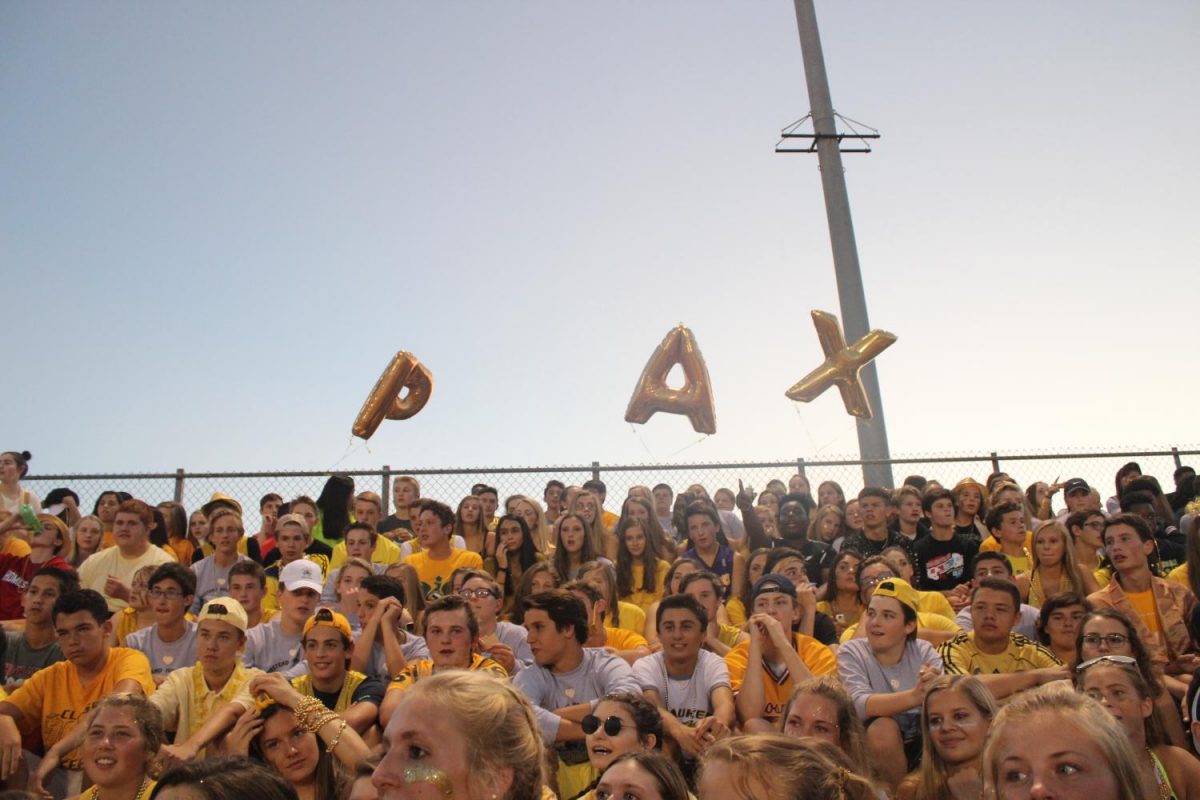 Gold balloons spelling PAX whirl above the student section.
