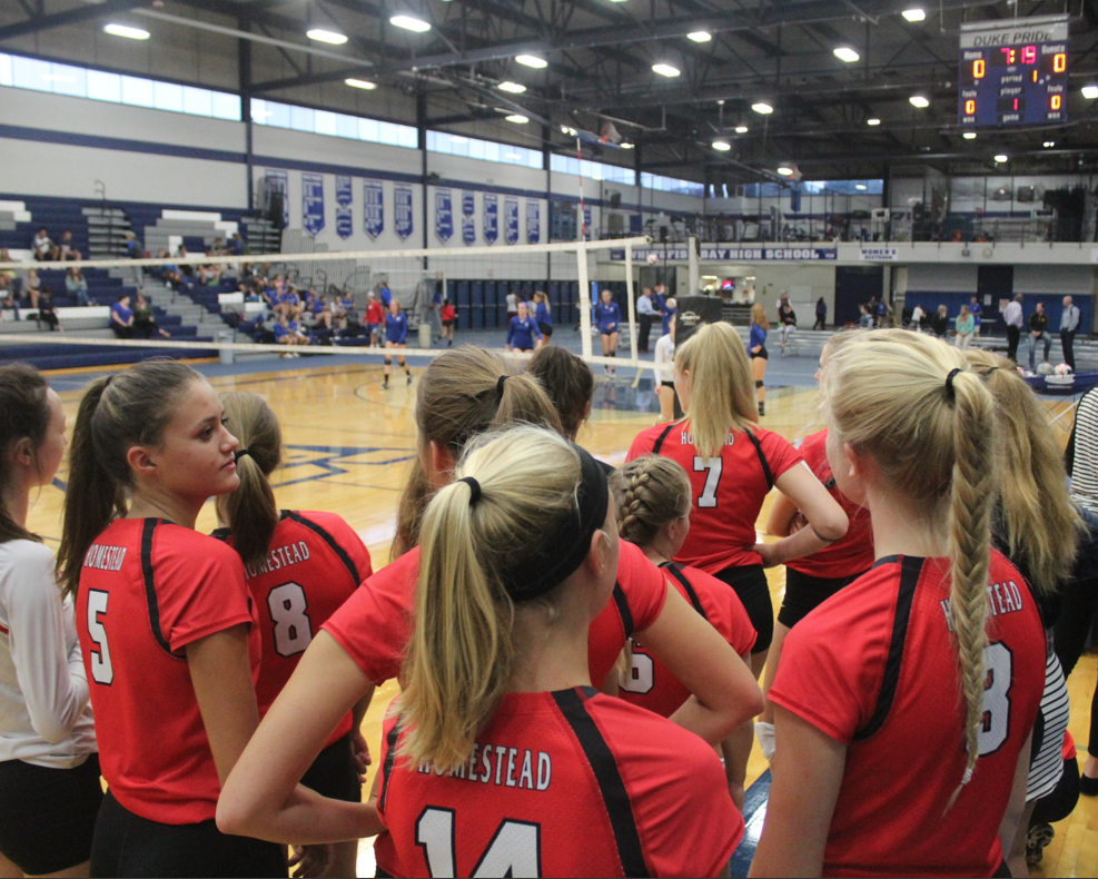 The girls volleyball team gathers together to size up the competition. 