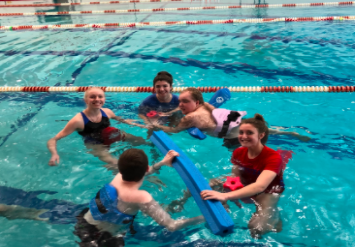 Anna Lalande and Hannah O’Brien, juniors, and Savannah Melan, senior, enjoy their time splashing around with the students in their adaptive physical education class. 