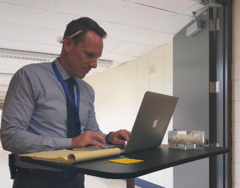 Principal Brett Bowers reads emails at his new rolling desk, newly outfitted with fresh mints for visitors.