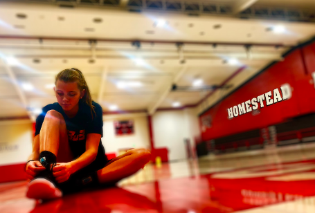 Grace Mueller ties up her basketball shoes as she gets ready to improve her skills at practice.