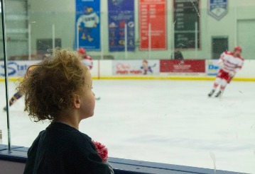 
Cayden Navarre attentively watches his dad coach the boys varsity hockey game. 
