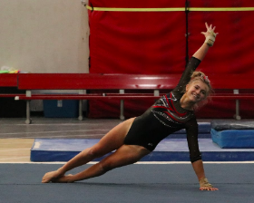 Annie Gebhardt, junior, smiles as she performs her routine on floor, her strongest event.