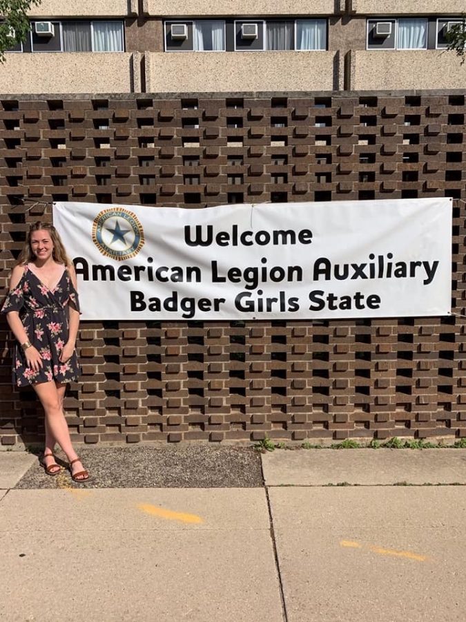 Bridget Brown, senior, smiles while standing next to the welcome sign