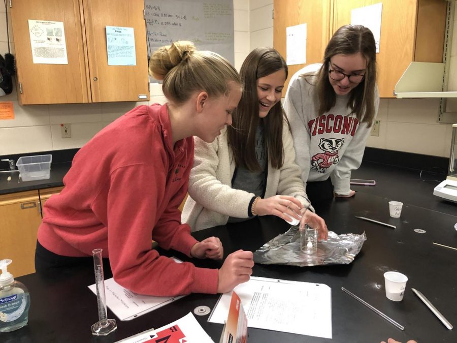 Annie Brown, Mary Bridget Jones, and Olivia Cragle, sophomores, mix chemicals to make a campfire.
