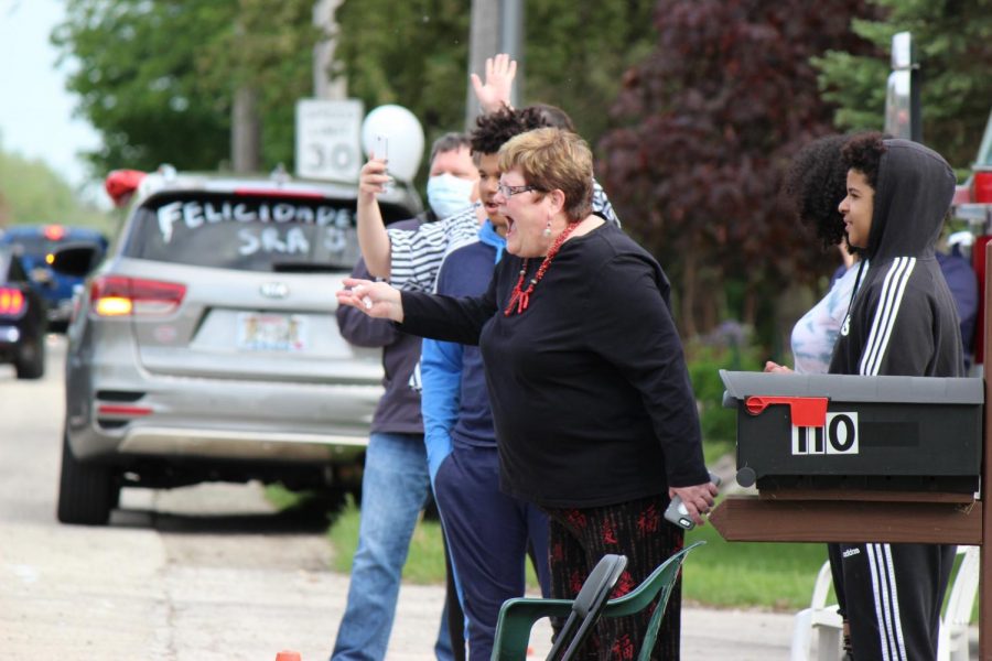 Kathy Solorzano stands outside her house and celebrates as students drive by.