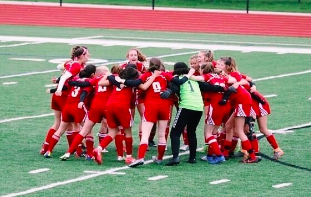 The girls huddle before their big game, doing a team chant from the 2019 season.