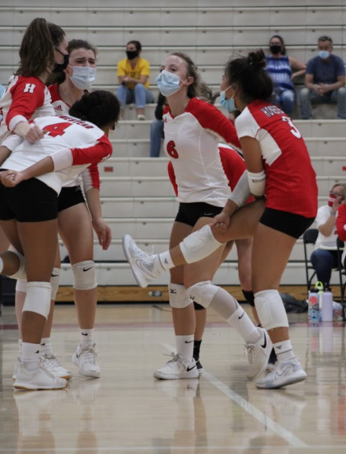 Girls varsity volleyballl celebrates in a team huddle after scoring a point against West Bend East Wednesday night. 