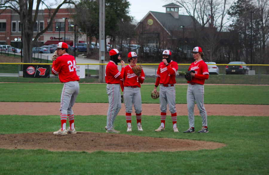 The team strategizes during their home game against Grafton while pitcher, Steven Yang, warms up.