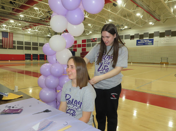 Maura Whitaker, co-chair, gets her hair cut by Emma Rader, senior for donation