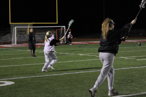 Assistant coach Rick Lee watches as Ava Grosso, junior, and Jozy Clark, senior, warm up on the field.  