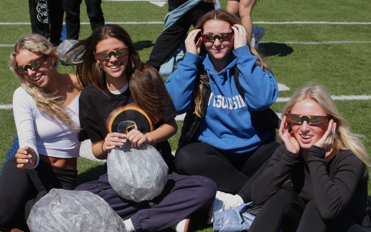 Staff and students watch the solar eclipse out on the football field during their fifth hour. 