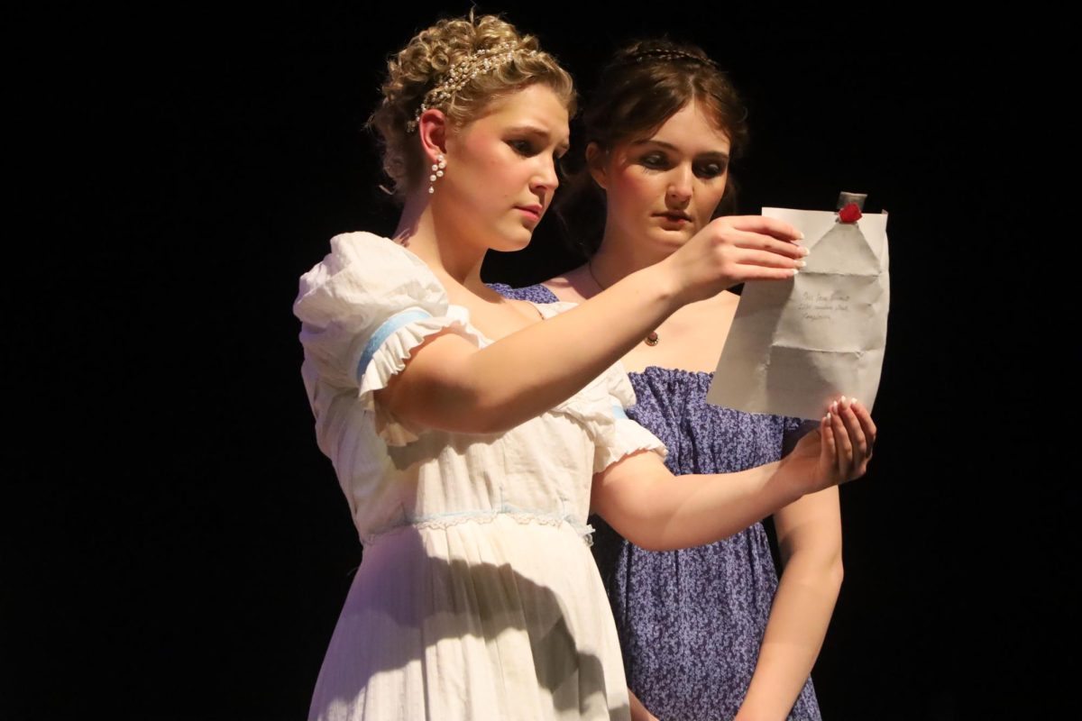 Jane Bennet, played by Emme Buesing, junior, shows a letter to her sister Elizabeth, played by Ryan Bennett, senior.