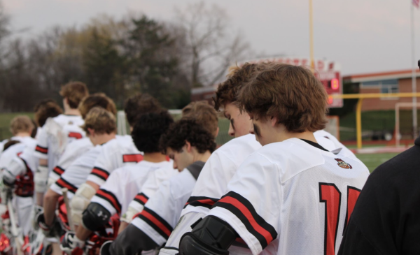 The boys lacrosse team lines up for the national anthem before the game begins.