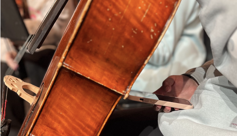 
A student in orchestra hides their phone behind their cello during a rehearsal.
