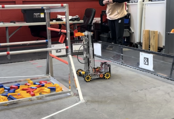 A robot scores a block by hanging it on a bar.