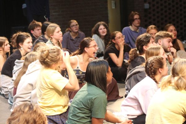 The cast of Pirates of Penzance gather to hear announcements after rehearsal.