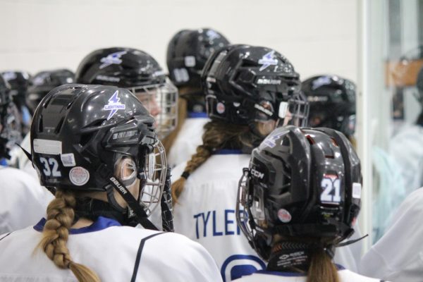 The team prepares for the game behind the barriers of the rink. 