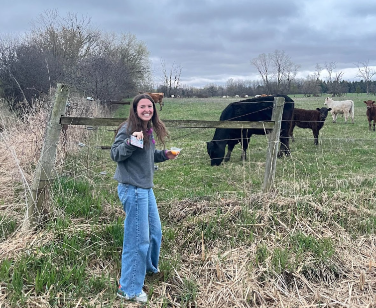Sofia Espinosa, Senior, smiles in front of a field of cows just outside of Mequon. 