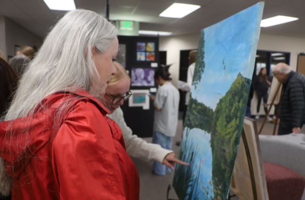 Meredith Niedfelt, Class of ‘25, and English Teacher Angelina Cicero observe one of Niedfelt’s paintings featured in Gallery Night. 

